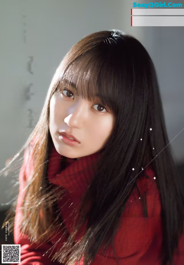 A woman with long black hair wearing a red sweater.