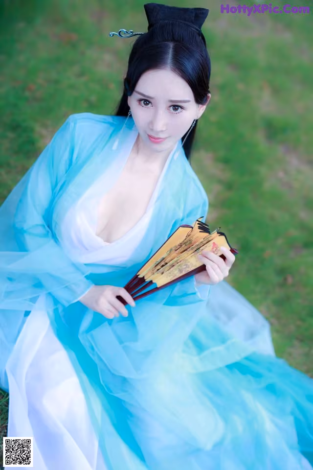 A woman in a blue and white dress holding a fan.