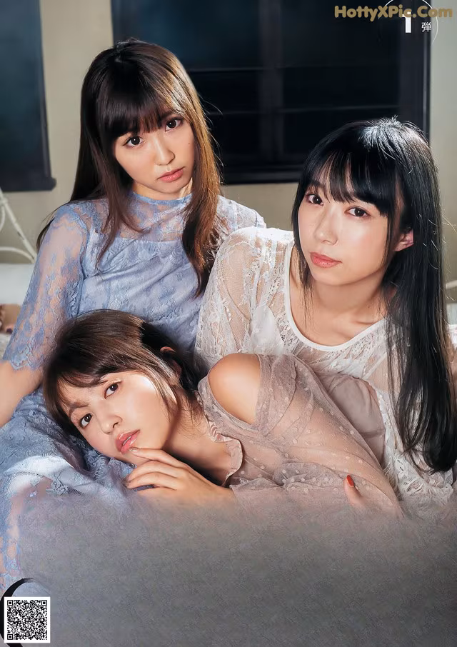 A group of three women laying on top of a bed.