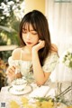 A woman sitting at a table with a cup and saucer.