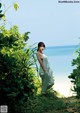 A woman in a white dress standing on a beach.