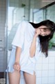 A woman in a white shirt is standing in a bathroom.