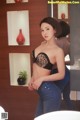 A woman in a black bra and jeans standing in front of a mirror.