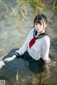 A woman in a white shirt and black skirt sitting in the water.