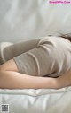 A woman laying on a bed with her back to the camera.