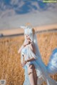 A woman in a white dress standing in a field.