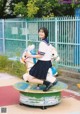 A woman in a school uniform riding a horse on a carousel.