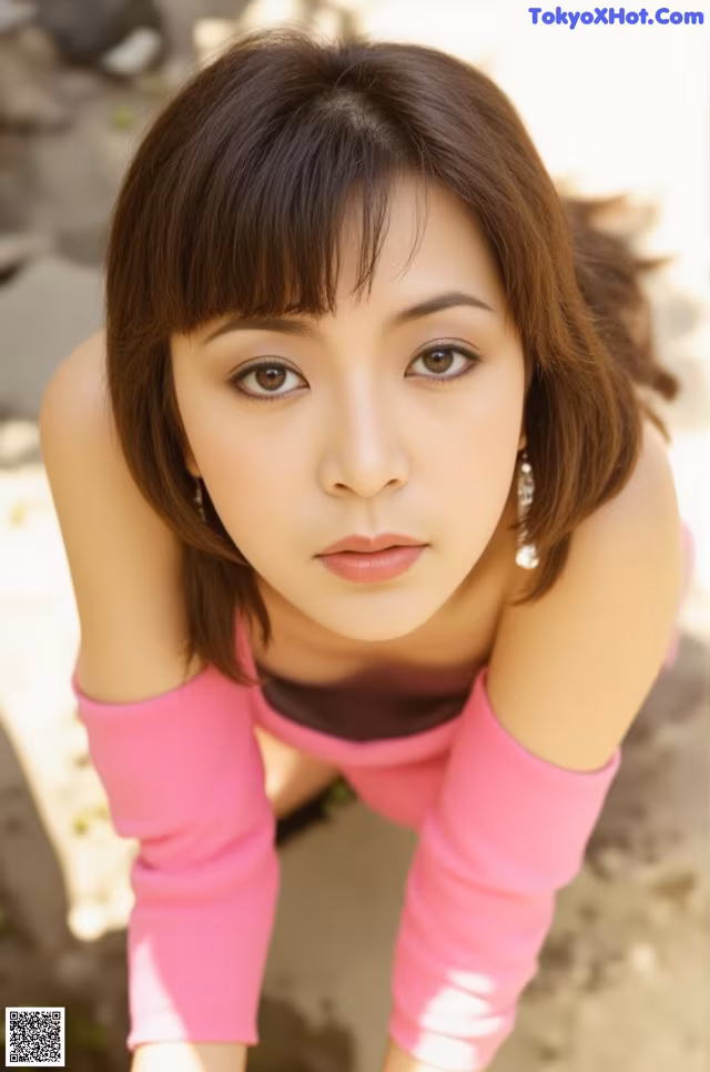 A woman in a pink shirt is posing for a picture.