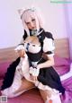 A woman in a maid outfit sitting on a bed.