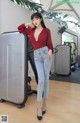 A woman in a red top and jeans posing in a gym.