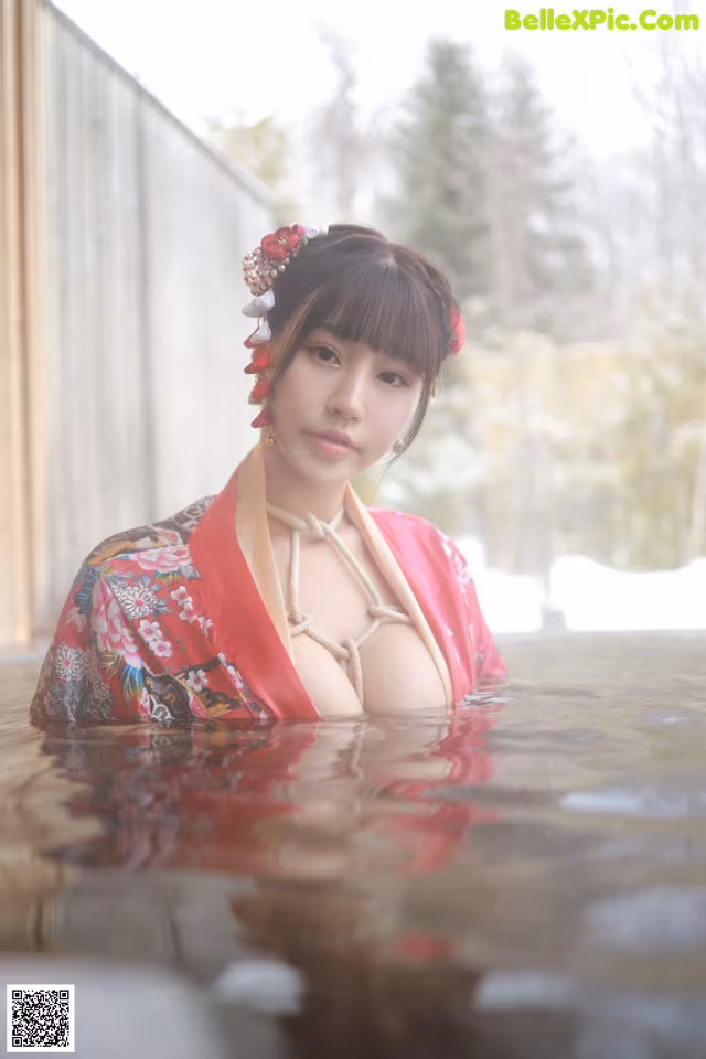 A woman in a red kimono is standing in the water.
