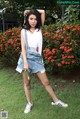 A woman in overalls and a t-shirt holding a rake in the grass.