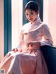 A woman in a pink dress sitting on a window sill.