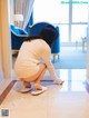 A woman crouching down on the floor looking at her cell phone.