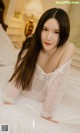 A woman in a white dress laying on a bed.