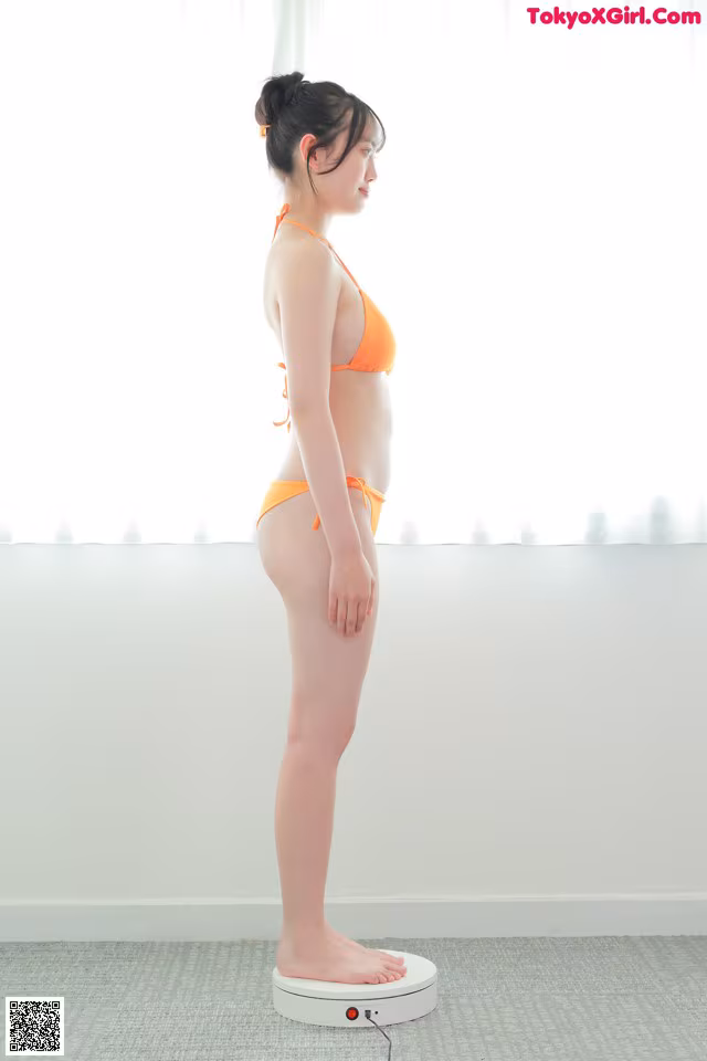 A woman in an orange bikini standing on a scale.