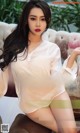 A woman in a white shirt sitting on a couch.
